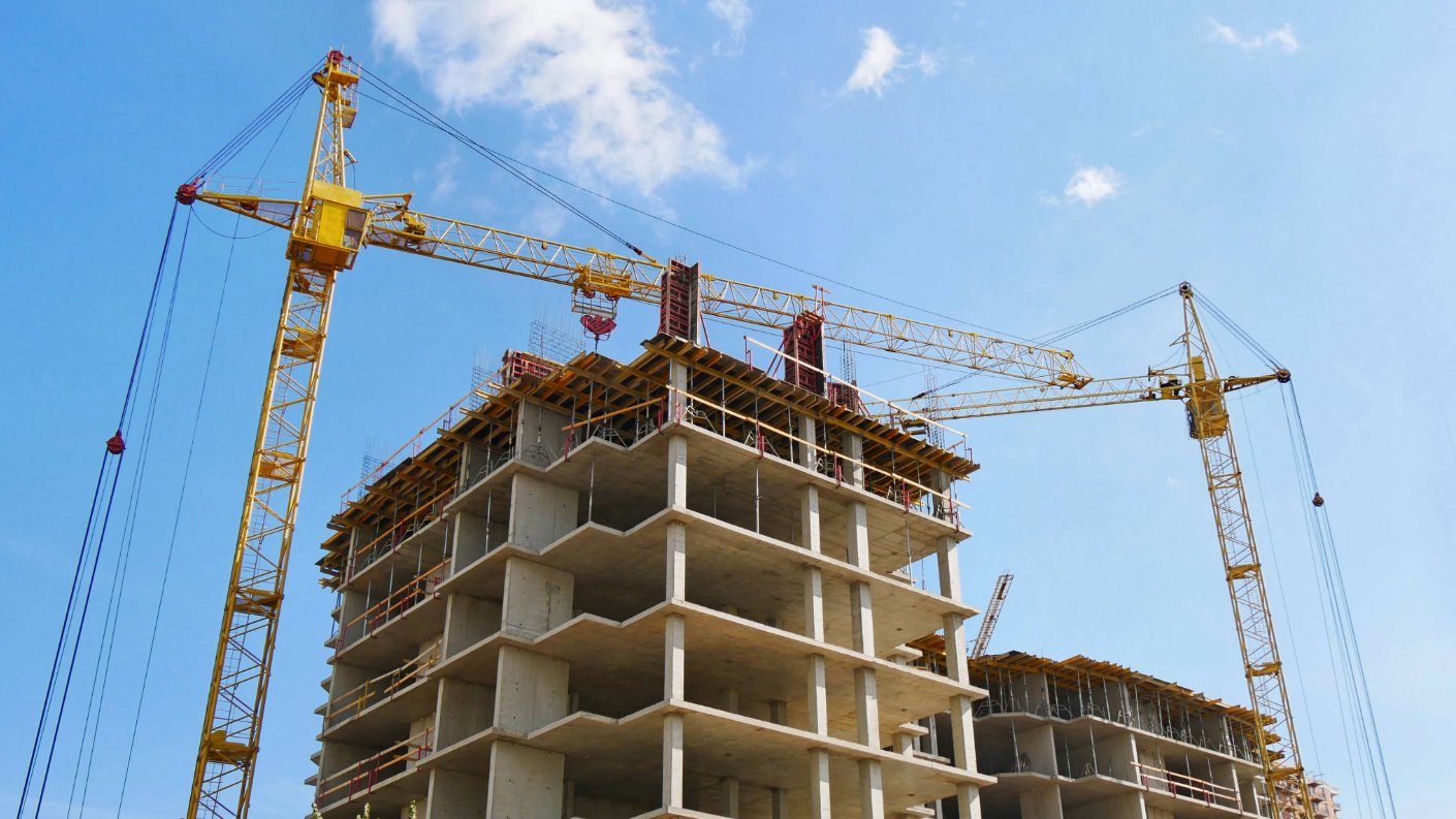 Concrete building under construction with tower cranes on site